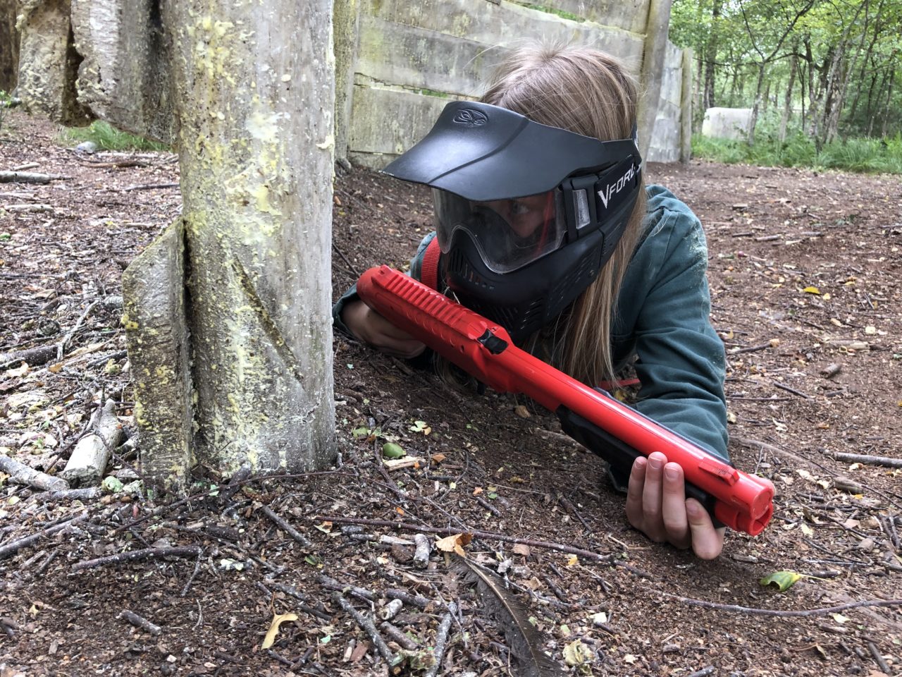 Meisje sluipt door paintballbos en houdt de tegenstander in het oog.