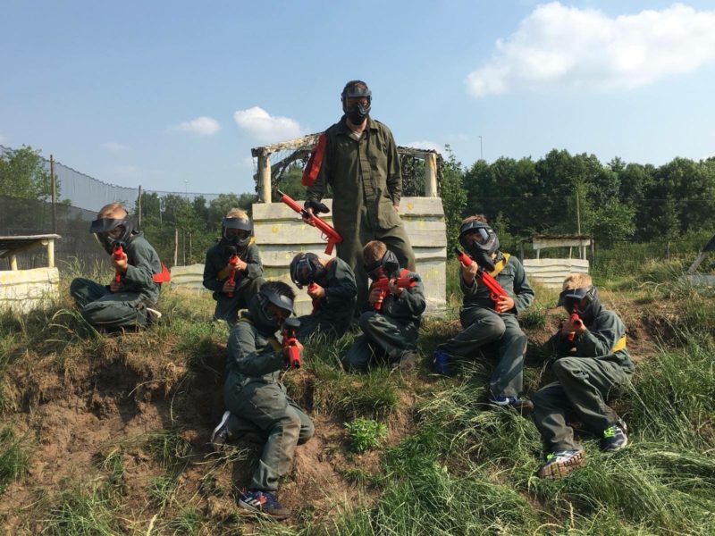 Team kinderen zitten op bult in kinderpaintballveld