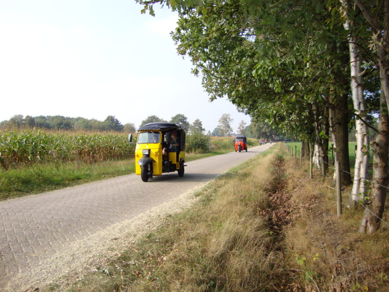 Gele Tuktuk rijd door Twents landschap